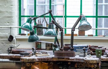 A close up of 4 lamps and tools on a workbench.