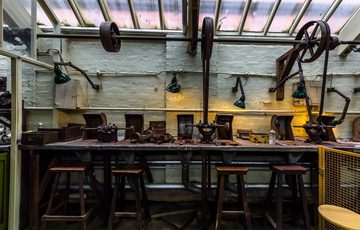 A workbench with stools and tools in an historic workshop.