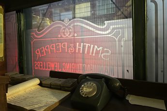 Telephone and paper on table in front of a window with Smith & Pepper sign on it.