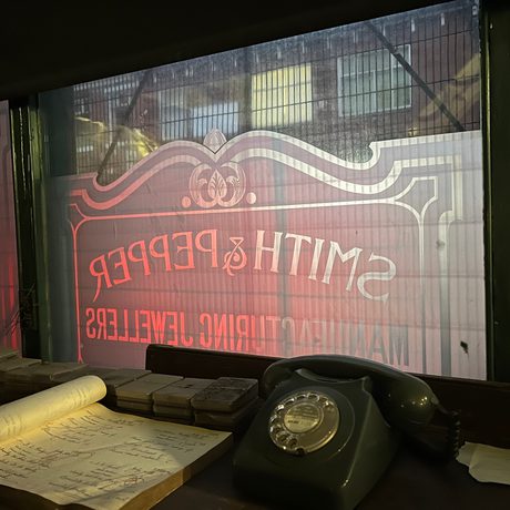 Telephone and paper on table in front of a window with Smith & Pepper sign on it.