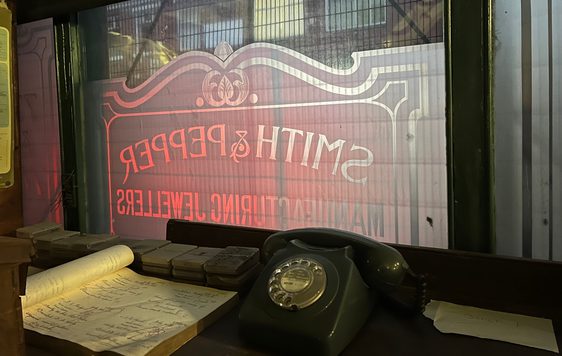 Telephone and paper on table in front of a window with Smith & Pepper sign on it.