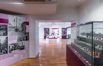 A gallery space with black and white photos on the wall and a cases of objects