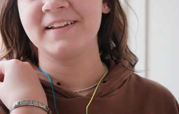A teenager modelling a pendant necklace and bracelet that has been made.
