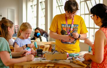 A group of people, including a child, engaged in a hands-on crafting workshop.