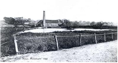 Old plack and white postcard showing Sarehole Hole Mill, which is seen at a distance from the road. There is a pond in front of the Mill, and it looks to be a rural area
