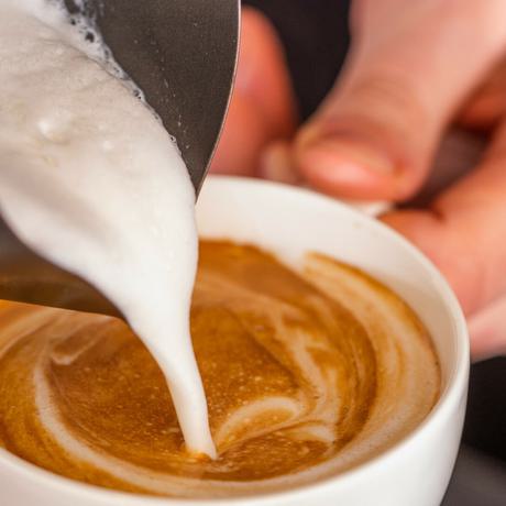 Milk being poured into a cup of coffee