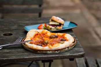 Pizza with olives on a plate resting on a wooden outdoor table
