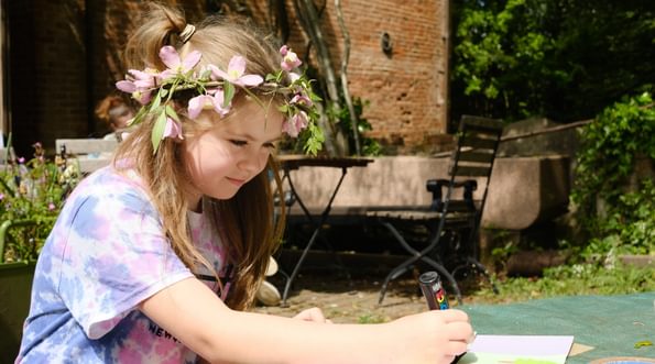 A child sitting at a table drawing on a piece of paper.