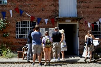 A group of people in the cobbled courtyard with Sarehole Mill building behind.