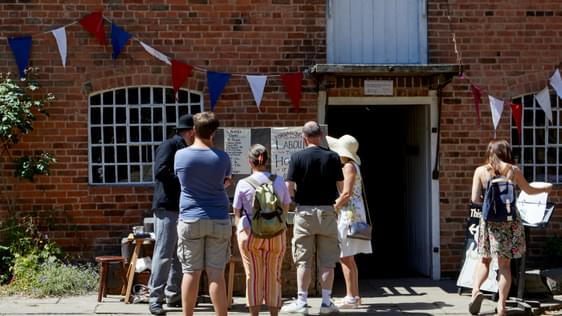 A group of people in the cobbled courtyard with Sarehole Mill building behind.