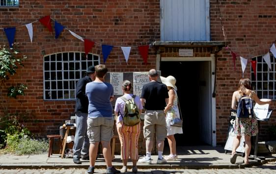 A group of people in the cobbled courtyard with Sarehole Mill building behind.