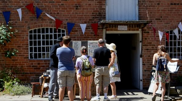 A group of people in the cobbled courtyard with Sarehole Mill building behind.