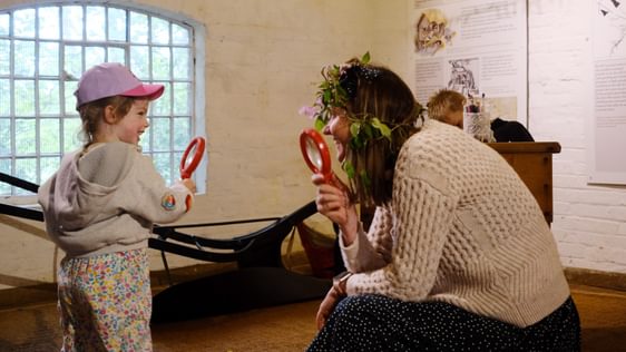 An adult and child smiling while looking through magnifying glasses while inside the mill.
