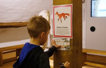 A child touching an interactive on the wall inside the mill building.