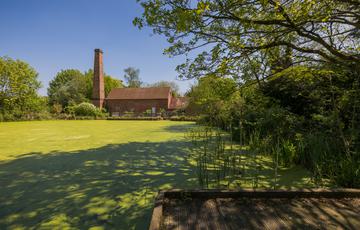 Distant view of Mill in front of pond surrounded by trees