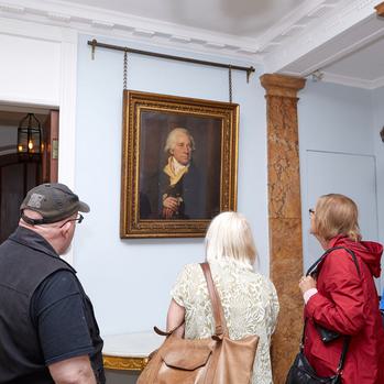 Three people inside Soho House looking at a portrait of Matthew Boulton that hangs on the wall