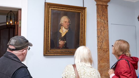 Three people inside Soho House looking at a portrait of Matthew Boulton that hangs on the wall