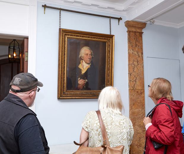 Three people inside Soho House looking at a portrait of Matthew Boulton that hangs on the wall