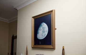 A pastel drawing of a the moon hanging on the wall.