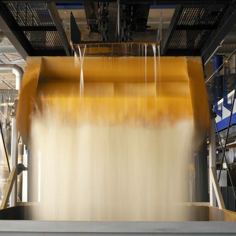 Close up of water pouring from the top of a steam engine into a bucket then into a hopper at the bottom