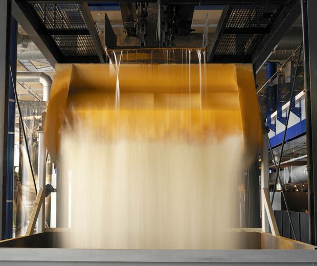 Close up of water pouring from the top of a steam engine into a bucket then into a hopper at the bottom