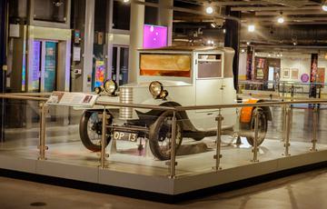 Front view of a car dating from 1927 on display with glass railings around it.