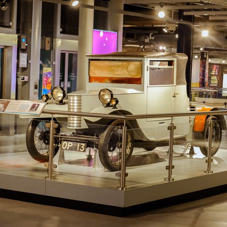 Front view of a car dating from 1927 on display with glass railings around it.
