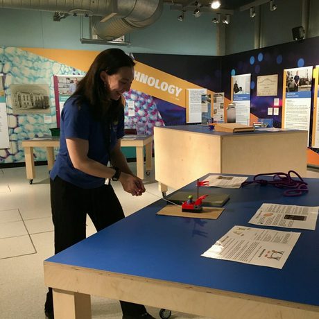 A staff member demonstrating forces by pulling a toy car along a table.