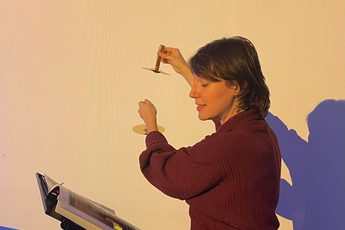 A staff member sitting while reading a booking and holding a musical instrument.