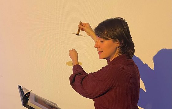 A staff member sitting while reading a booking and holding a musical instrument.