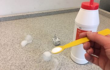 Experiment: Salt being spooned into a beaker.