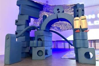 An arched structure made out of foam blocks of different shapes.