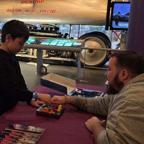 A person sitting at a table interacting with a child.