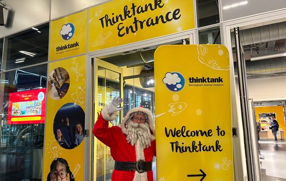 Santa at the entrance to Thinktank with sign that reads 'Welcome to Thinktank'.