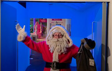 Santa with his hands in the air in front of the MiniBrum entrance.