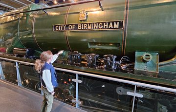 A child pointing to the City of Birmingham train on display.