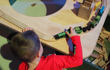 A child playing with a wooden train toy on a table.