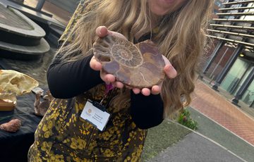 A person with a look of amazement, holding a fossil.
