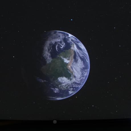 Earth projected onto a Planetarium ceiling with seats underneath.