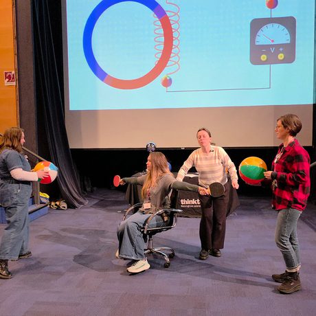 A group of staff with propers and on a chair performing a science show.