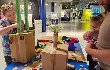 An adult and two children making cardboard box sculptures.