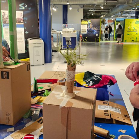 An adult and two children making cardboard box sculptures.