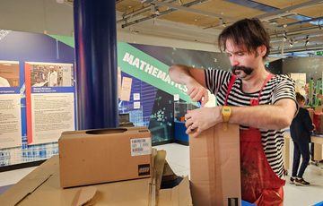 A person creating a cardboard box sculpture.