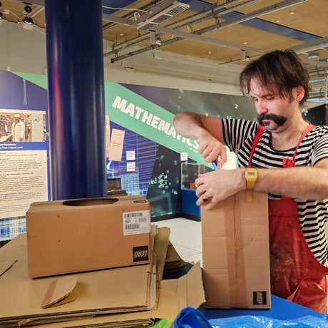 A person creating a cardboard box sculpture.
