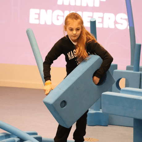A child carrying large foam blocks.