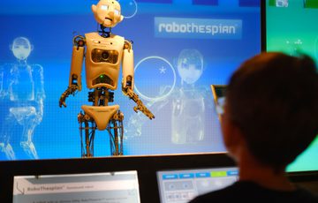 A humanoid robot named RoboThespian interacts with a child in the Futures exhibit.