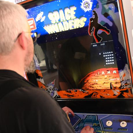 A person playing on Space Invaders gaming machine.