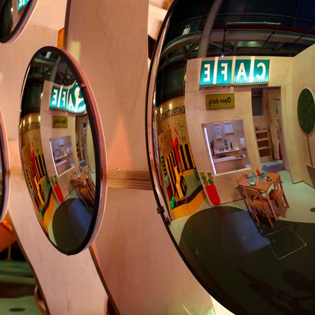 Mirrored circle disks with a play café area reflected in them.