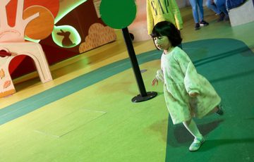 A child running around a play race track area.