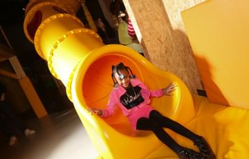 A girl sitting at the end of a tube slide.